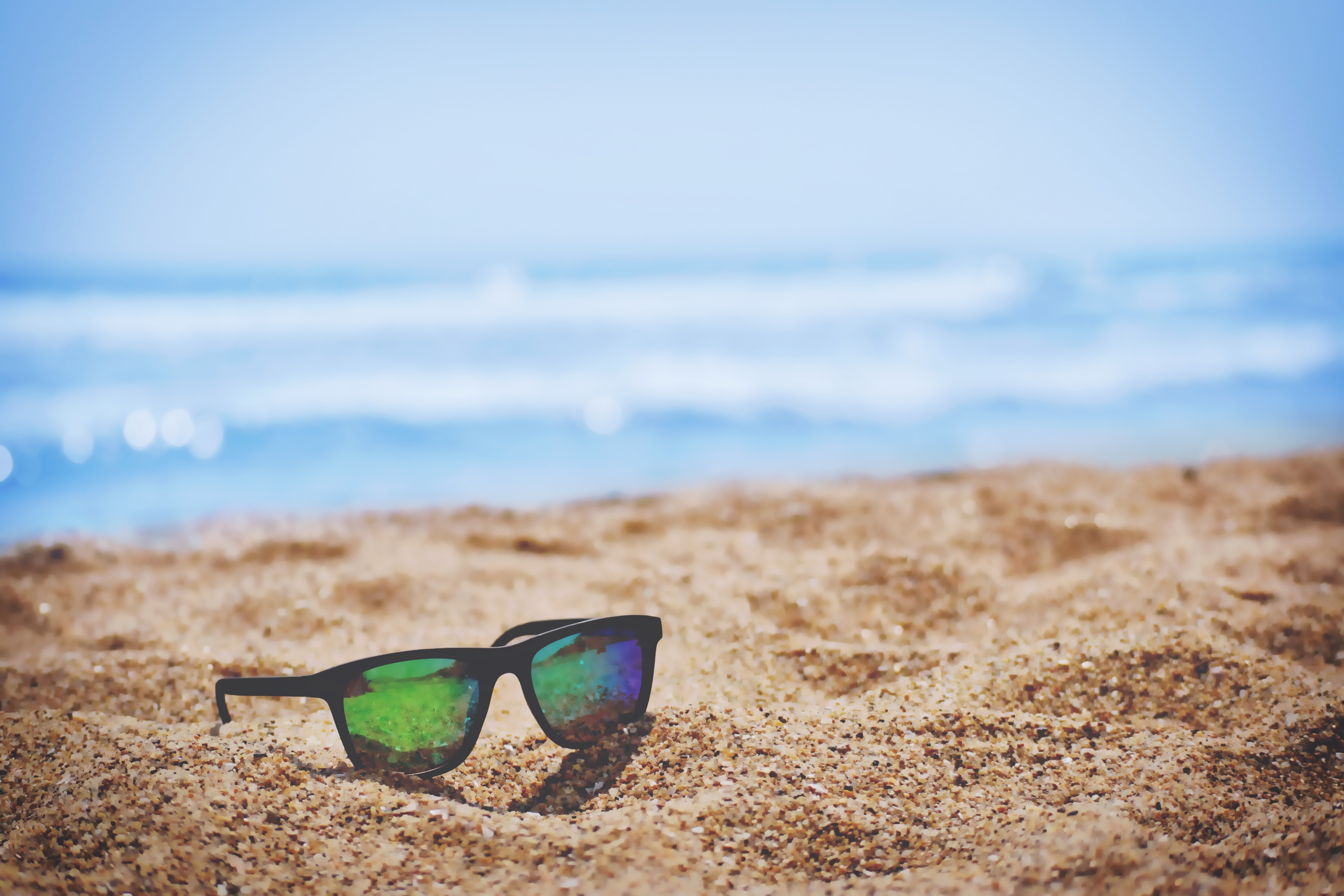 sunglasses in the sand with ocean in background
