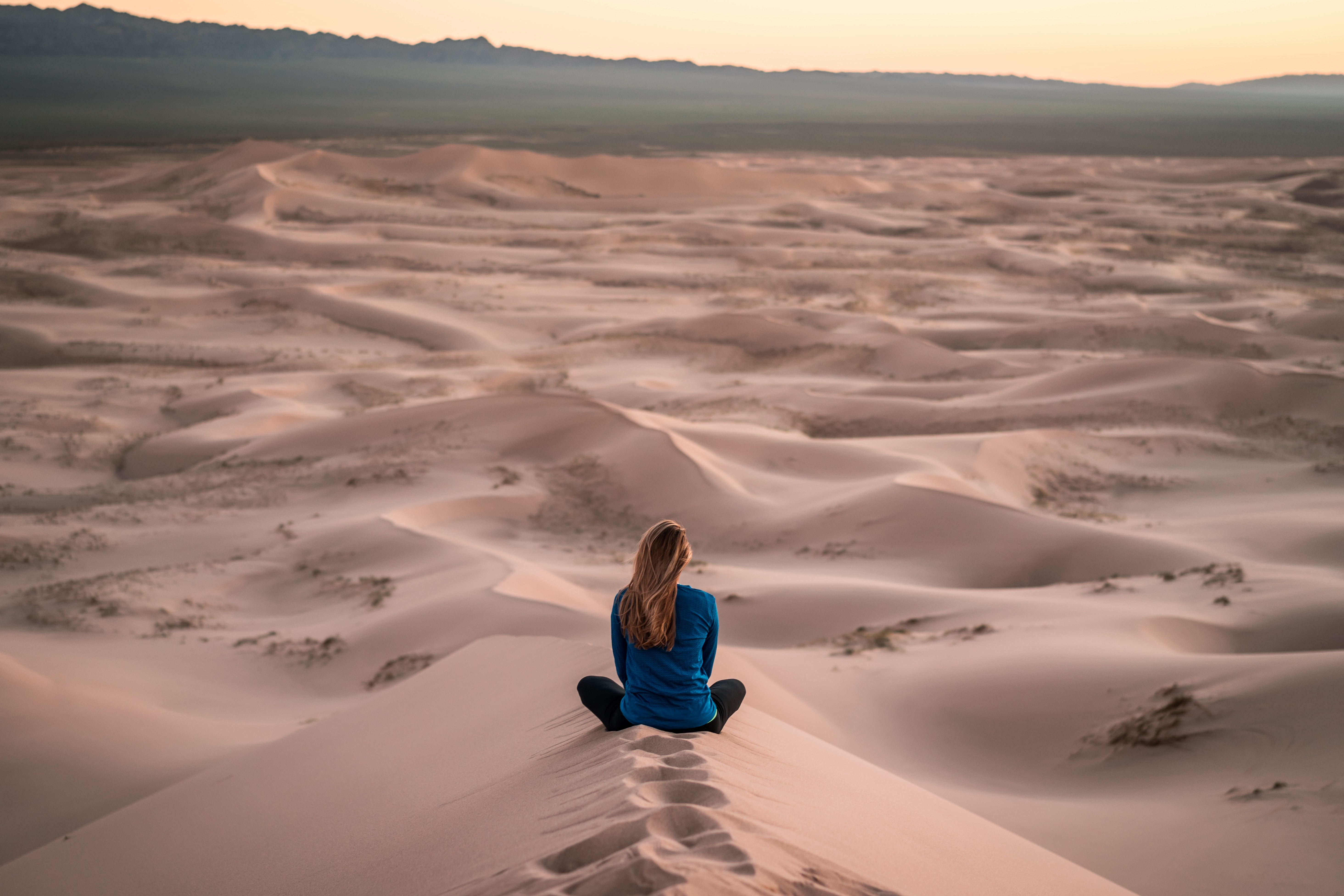 lonely woman sitting on a sand dune in desert