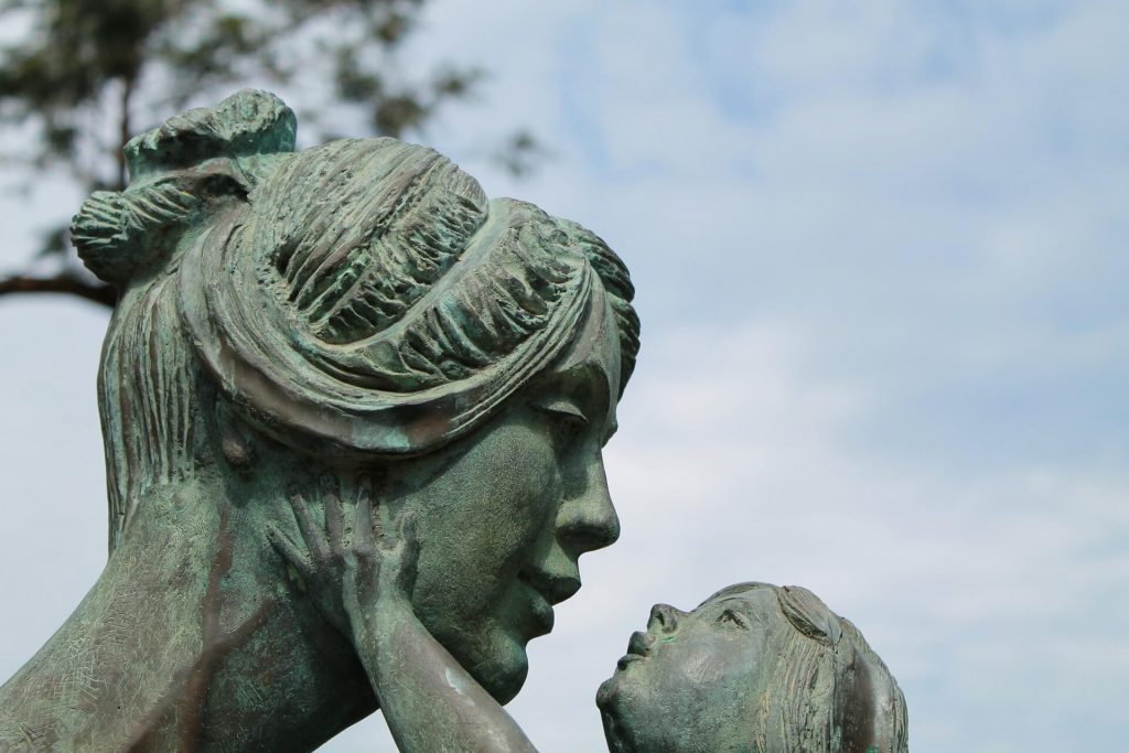 green statue of mother gazing at child