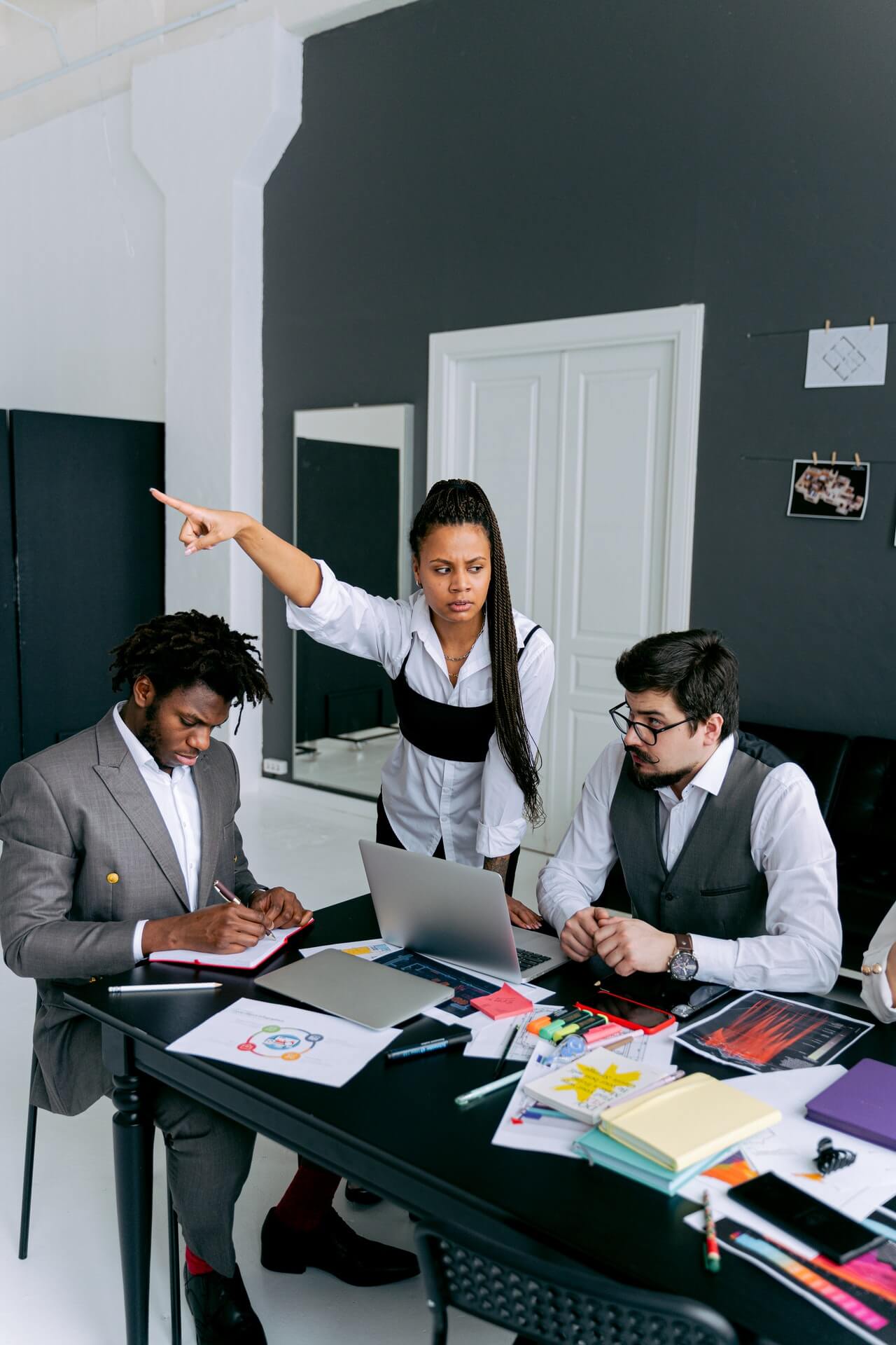 angry woman boss pointing while male employees look uncomfortable