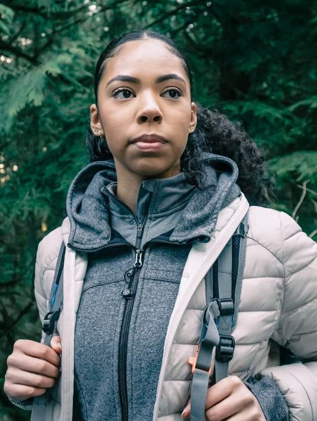 young woman wearing a backpack, hiking but stopped and gazing into the future